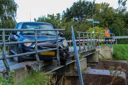 Auto botst tegen hekwerk van brug en komt boven water tot stilstand aan de Langereis